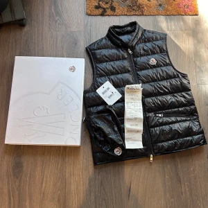Moncler Gui Väst - Moncler Gui väst i nyskick, kommer med box, dustbag, kvitto och tag. Storlek 4 passar M/L, nypris 8400 mitt pris 4100 men tar emot rimliga bud! Över 80 refs finns! :)