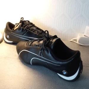 BMW skor Puma - Säljer, ett par BMW skor som köptes från butik för 499kr, men sedan användes bara 3 gånger. Helt rena och nya. Inga smuts men endast ett skratch på loggan som man kan se bild 2.   Säljer dem för endast 250kr🔥....Priset kan sänkas😉. Storlek 38(EUR).