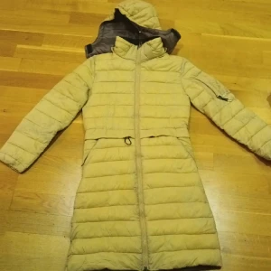 Ridkappa CRW - Säler ridkappa från CRW Hööks i fint skick. Jackan är ljus beige och tyvärr lyser fyllningen igenom på vissa ställen. Tvättas innan leverans. Avtagbar kapuschong. 