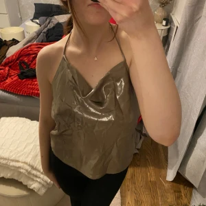 linne - Glittrigt guldigt linne som knyts runt halsen. Öppen rygg och går att justera banden lite