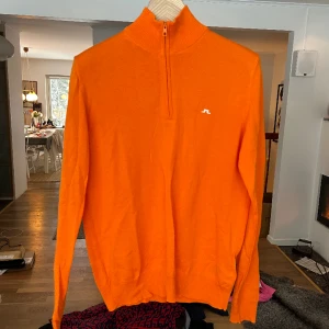 Pullover halfzip J.Lindeberg - Halfzip pullover i skitsnygg orange nyans från j.lindeberg. Storlek m för herr, oanvänd.