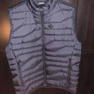 J Lindberg väst - Hej! Säljer denna svarta och stilrena västen från J Lindberg. Den är använd några få gånger utan några defekter på den. Den har storlek XL men sitter bra på dom som har L i storlek också. Tveka inte vid frågor! Priset kan diskuteras vid snabb affär.