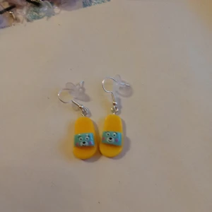 Örhängen med hänge av en sandaler . - Tuffa örhängen med hänge av sandaler .helt nya och oanvända .