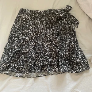 kjol - säljer den här svarta kjolen med vita prickar på, köpt här på plick pga att den inte kommer till användning⭐️som man ser på andra bilden så knyter man den i hörnet💞kontakta om du har några frågor🫶🏼