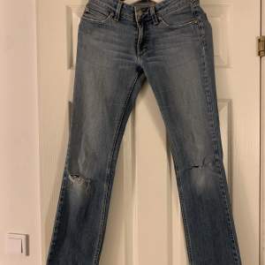 Ett par Lågmidjade vintage jeans som har två hål på knäna.