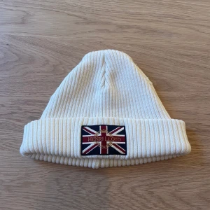 Henri Lloyd Mössa - Vit Henri Lloyd mössa, skicket är grymt men har små skavanker som är enkel att fixa!