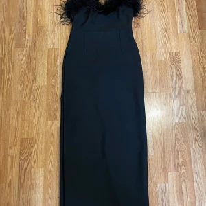 Svart fest klänning med fjäder 🪶👗 - Superfin klänning med fjäder långtuppe vid brösten. 👌klänningen har använts 1 gång och är i storlek XL men kan användas som L