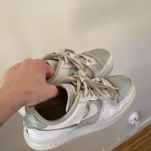 Nike air force 1 LXX - St 38. Vita och ljusblå nike Air Force 1. Väl använda så dem är lite skitiga tyget, jag har rengjort dem så gott det går. Det är även hål i innetyget i hälen men annars inga andra skador.