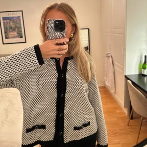 Stickad kofta - Stickad kofta i svart/vit med guldiga detaljer på knapparna. Storlek L men passar mig som har s