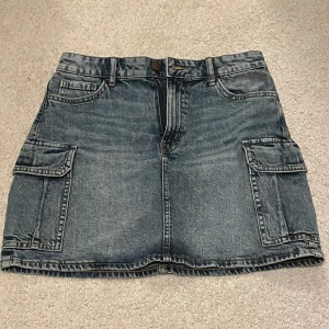 Söt Jeanskjol - Jeanskjol jag säljer då den inte används. Den har inga defekter och köptes på barnavdelningen men passar mig som är storlek S. Den är ca 38 cm lång och man kan justera midjemåttet med ett band man kan se på bild 3.