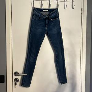 Ett par marinblåa skinni jeans från Redial Paris med rosetter på anklen. Storlek xs/34. (Väl använda). Rosetternas pärlband är lite av samt knappen på framsidan sitter lite löst med den går att laga. 