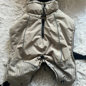 Feel Active Voss Parka Beige (30 cm) - Varm och vattentät. Går att justera till rätt passform både kring hals, rygglängd, bröstet samt bakparti för hundar med kortare ben. Dubbel dragkedja som både underlättar på- och avklädning samtidigt som den låter hundens koppel komma ut där.