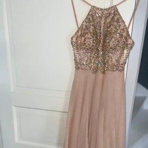 Balklänning  - Beige/brun balklänning med stenar i nyanser av guld, rosé & silver. Skimrar otroligt fint i dagsljus!  Från Dressroom Linné.  