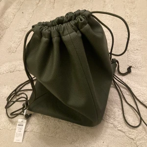Ryggsäck Väska | Militär Läderfärg  - Petit Soft Mini Bag 🤩 är en liten väska för ett stort tillfälle. Det mjuka lädret rymmer alla nödvändiga tillbehör för en oförglömlig kväll. Remmen, som gör att den kan bäras på axeln, crossbody eller till och med i handen, en snygg pärla för att kom
