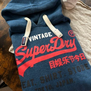 Tjock Vintage Superdry Hoodie  - Jätte tjock och varm hoodie från Superdry Vintage! Insidan är hur mjuk och mysig som helst och sitter jätte skönt.  - Högkvalitativ och perfekt som oversize hoodie då den är i storlek L men även kan sitta bra som M.