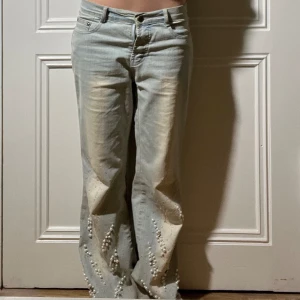 Unika Lågmidjade ljusblåa jeans med pärlor! - Säljer dessa as coola ljusblåa Lågmidjade bootcutjeansen. De har påsydda pärlor och kristaller från knäna och nedåt. Dragkedjan fungerar inte men är ersatt med en tryckknapp så jeansen går att stänga och det ser normalt ut. Säljer pga för stora🥰