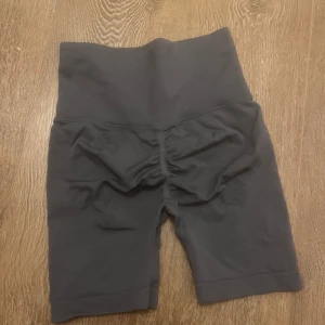 Träningsshorts - Träningsshorts storlek s/xs. I gråblå färg med scrunch bak. Sköna och stretchiga, i bra skick endast ett litet hål vid höften som inte syns på längre håll🩵