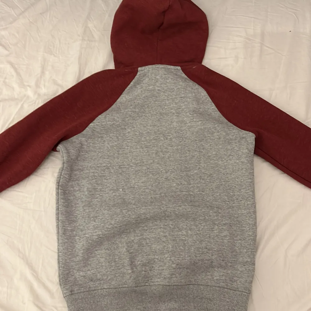Röd/grå hoodie från Superdry i storlek S. Köpte den för ca 1 år sen men har knappt använt den. Säljer nu eftersom den inte riktigt passar mig längre.. Hoodies.