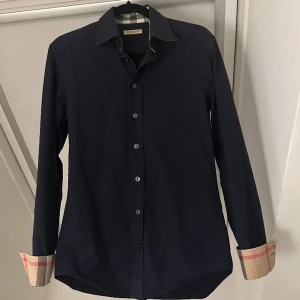 Burberry skjorta - en skön trendig skjorta i 10/10 skick i färgen mörk blå. Inga fläckar eller defekter. Är sparsamt använd. nypris ca 5000kr.  passar dig som är 170-175cm lång! hör av er vid frågor&bilder🤝🏽🙌🏽