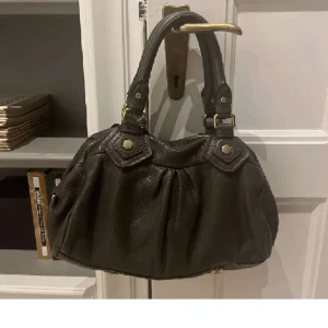 Marc jacobs väska - Säljer min kompis as najsiga marc jacobs väska! Den e i en skit najs färg, typ mörk grå! Mått: Höjd 22cm, längd 33cm💓 Bra skicka, förutom att lite läder lossnat på ena handtaget men inget man tänker på! ⭐️