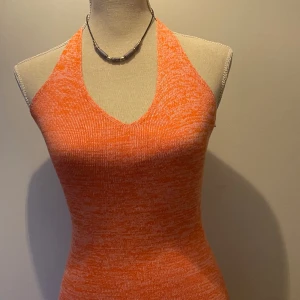 Halterneck klänning - Köpt på bikbok, knappt använt och inga defekter!🩷färgen på klänningen är orange med lite inslag av rosa. Materialet är ish stickad men mjukt och skönt. Dm vid intresse/frågor!💕