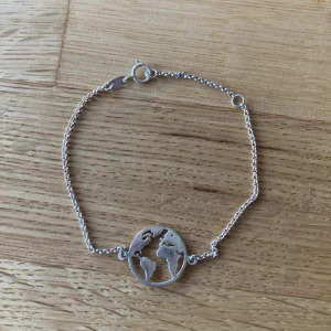 Armband med jordglob - Silvrigt armband med jordglob. Ganska liten storlek, precis under 18cm långt.