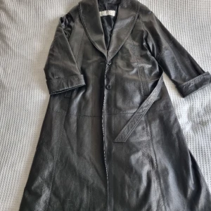 Givenchy Svart Läderjacka - släpp loss modedjuret - 🌟 Dramadrottningen av Jackor: Presenterar garderobens grandiosa diva – en vintage Givenchy svart läderjacka som är här för att stjäla rampljuset! Den är lång, den är svart, och den ber nästan om att bli filmad i närbild. 