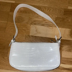 Liten väska - Fin vitt mini väska med mönstrade detaljer på. Använd fåtal gånger. Säljer pågrund av att jag inte har någon användning av den. Köparen står för frakt 💕