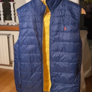 Ralph Lauren väst  - Oanvänd tvåsidig Ralph Lauren väst  Storlek : Barnstorlek XL  Färg : Mörkblå och Gul  Nypris : Hittar inte  Säljer för 400 kr 