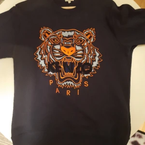 KENZO Black on Orange - Classic Kenzo Crewneck  with an incredibly intricate and detaljed embroidery of a tiger on the chest. Of course authentic, good condition, almost brand new, see the pictures. Size S but also fits M Price, new: 2200 SEK ~200€
