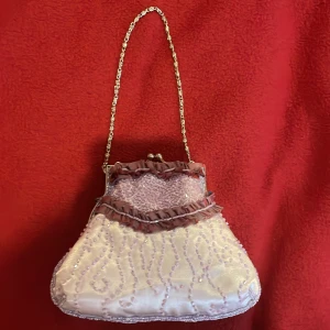 Lila festväska - Väldigt gullig och fin väska som man kan inte får plats med jättemycket men det som man brukar behöva. Helt ny! Aldrig använd. Väldigt fina detaljer. Lappen sitter på fortfarande. Ett inre fack i väskan. Passar perfekt till många olika färger!❤️