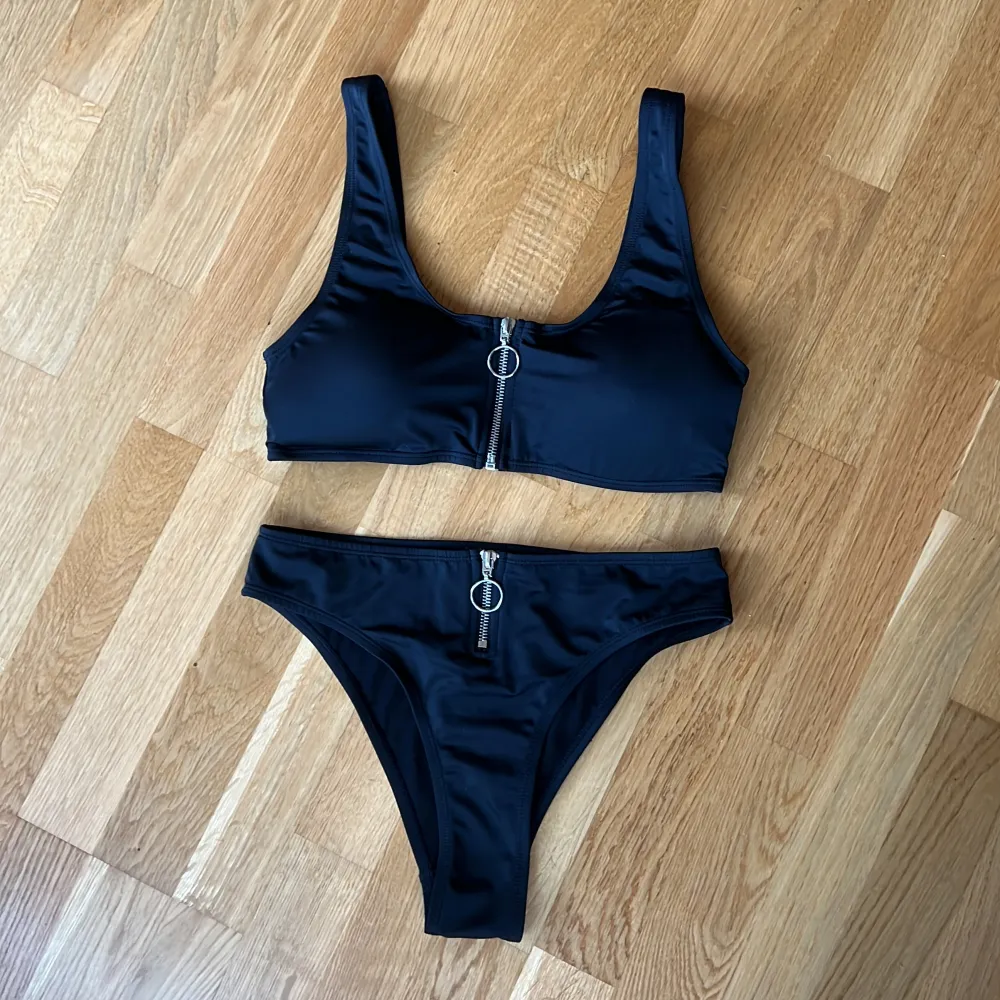 Svart bikini från Nelly Beach med snygga dragkedje-detaljer! Använd ett få tal gånger så den är i väldigt fint skick, 9/10😍 Underdelen är i storlek S och överdelen i storlek M! Inläggen i överdelen går att ta ut om man vill det👍🏼Pris kan diskuteras🌸. Övrigt.