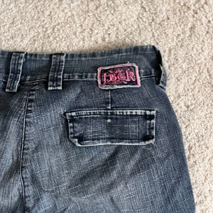 Cargo jeans - Skitcoola Cargo jeans med rosa detalj. Dragkedjan funkar inte men det är enda defekten annars supersnygga. 