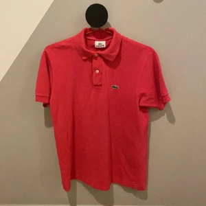 Lacoste Piké  - En stillren Lacoste piké i färgen rosa. Fint skick! 100% Bomull. I stolek S Herr. Hör gärna av er vid frågor eller funderingar! Pris går att sänka.