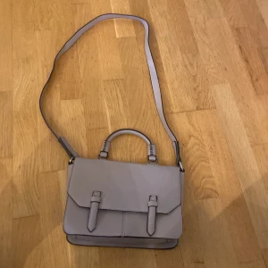 Mörk lila/rosa väska  - Väskan kan både vara en handväska och en axelväska då man kan dra av den långa kedjan köpt från Åhléns för ca 15år sedan och knappt använd