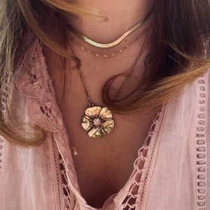 Blomhalsband Pilgrim - ett superfint guldhalsband från pilgrim som inte går att köpa nytt, en fin rosa sten i mitten och halsbandet är ungefär 50 cm långt och justerbart, blomman e ungefär 2x2 cm🤩