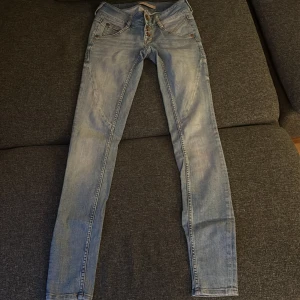 Low waisted Ginatricot jeans  - Storlek 34, gammal modell, flera knappar, ljusblå, mönster på backfickan