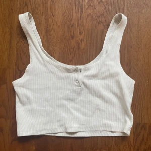 Vitt linne med knappar - Ett vitt linne från bikbok i storlek S. Den enda defekten på tröjan är två små hål vid toppen av baksidan som kan ses i bilden som kom när jag drog av lappen.