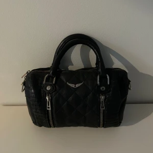 Zadig väska - Säljer en jättefin zadig väska! Den är i okej skick. Dragkedjan är lite sönder på kanten, se sista bilden. Men den går att öppna och stänga som vanligt. Tyget är lite slitet men fortfarande väldigt fin! Hör av er vid frågor!💕