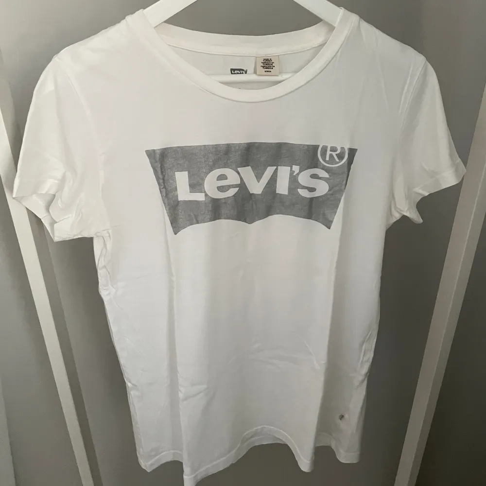 Vit T-shirt med silvrig Levis-logga från Levis i storlek S. Bra skick!✨ Köparen står för frakten, kan mötas upp i Kalmar!. T-shirts.