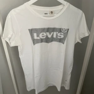 T-shirt från Levis - Vit T-shirt med silvrig Levis-logga från Levis i storlek S. Bra skick!✨ Köparen står för frakten, kan mötas upp i Kalmar!