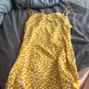Gul sommarklänning - En jätte fin gul sommar klänning med vita blommor. Slits i botten med dragkedja på baksidan. Klänningen är medellängd.