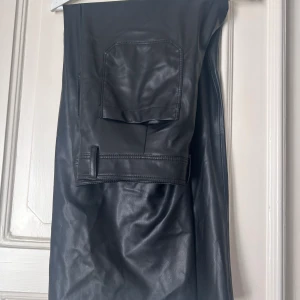 Läderbyxor  - Svarta byxor i läderimitation, aldrig använda. Ankellånga och vida nertill.