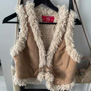 Beige Väst i shearling ull och suede från EDC. Storlek M men om man ska ha tröja/jacka under passar den en xs-s. Skicka gärna meddelande vid frågor. 