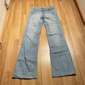 (39) helt perfekta ljusblåa lågmidjade bootcut jeans med detaljer på fickorna och kristallknapp. Midjemått rakt över: 36 cm, innerbenslängd: 85cm 🩵
