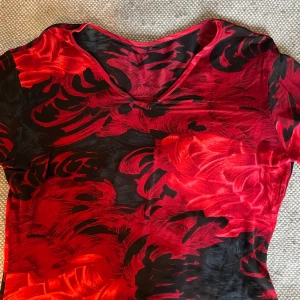 Meshtröja - Snygg mönstrad meshtröja i rött och svart, toppskick! Lite genomskinlig. Ganska tunn så superhärlig till sommaren. Finns ingen storlek men den är stretchig och inte tajt så skulle tro att den passar xs-l beroende på hur man vill att den ska sitta. 