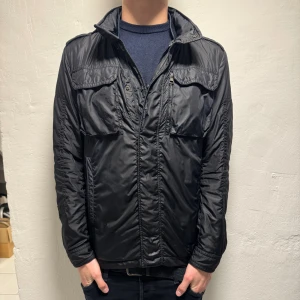 Moncler Fieldjacka - Tja säljer denna riktigt feta Moncler fieldjackan i storlek large men sitter som medium. Finns mini hål på fram se på bild 1 annars bra skick hör av vid funderingar!