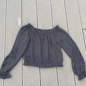 Svart blus - Blusen är kort, slutar lite ovanför naveln. Man kan välja att ha den som off shoulder eller dra upp den över axlarna 