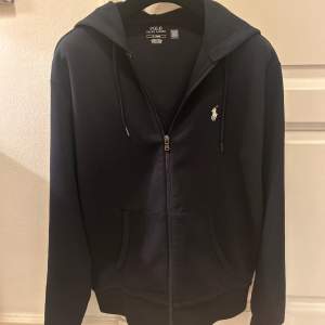 En riktigt snygg Ralph Lauren zip hoodie i färgen mörkblå. Köpt på NK i Stockholm för runt 2 månader sedan, men har ej kommit till användning. Skick 10/10. Modellen på bilden är 189 cm, väger 76 kg och när storlek M. Passar 177-189 skulle jag säga!🙌🏽😊
