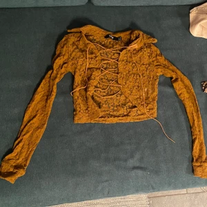 Jaded London orange topp i storlek S - Långärmad topp från Jaded London med snörning i genomskinligt material. Normal i storleken men inte stretch material. Är lite sliten men syns bara på väldigt nära håll